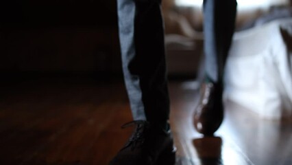 man in leather shoes walking around the room