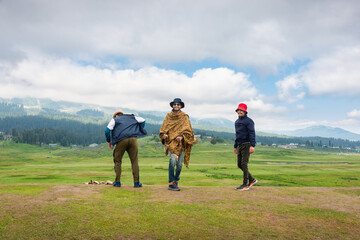 Three young adult man jumping on meadow, Gulmarg, Jammu and Kashmir, India.