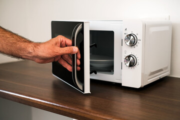 Fototapeta premium a man puts a plate in the microwave to warm up his food
