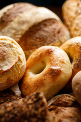 A close-up view of various types of traditional wheat and rye bread, focus on the bagel inside. 