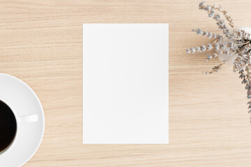 White invitation card mockup with lavender and a cup of coffee on the wooden table. 5x7 ratio, similar to A6, A5.