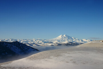 Elbrus is a high mountain. Dormant volcano. mountain covered with snow on blue sky background. Caucasus mountains. Fog and slopes