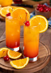 Tequila sunrise cocktail with orange slice and cherry