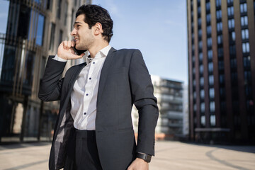 The manager is a happy man talking on the phone going to work in the office in a business suit