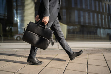 A man carries a bag briefcase goes to work in the office in a business suit