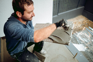 Professional construction worker placing tiles on waterproof balcony