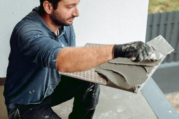 Professional construction worker placing tiles on waterproof balcony