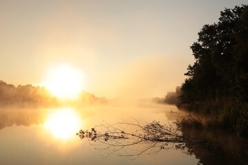 Fototapeta na wymiar Sunrise over a lake on a foggy spring day