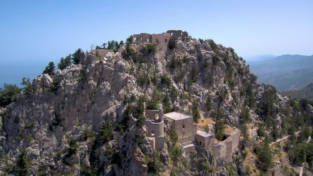 Very high historical castle "Buffavento" in Northern Cyprus aerial view zoom out from castle, Mediterranean Sea and city of Kyrenia on the background 