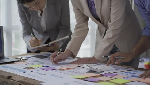 Businessmen and business women in Asia brainstorm on new document finance project colleagues working together to plan teamwork success strategies in a modern office 4k.