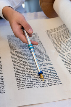 A Boy Reading From The Torah During His Bar Mitzvah Celebration In Israel, Holds A Silver Yad, A Pointer Used To Guide The Reader Through The Ancient Hebrew Text.