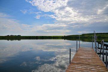 Naklejka na ściany i meble dock overlooking on a calm lake with reflecting sky