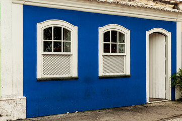 Fototapeta na wymiar Old house in blue color and white details with white wooden door and windows. Nice facade. City of Porto Seguro. Bahia.