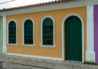Old house in orange color and green door and windows. Details in white. Nice facade. City of Porto Seguro. Bahia.