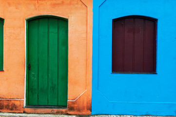 Old orange house and green door next to another blue house and burgundy window. Beautiful facades. City of Porto Seguro. Bahia.