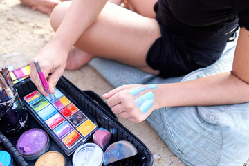 Artist trying out shades of color on her skin during a body paint session.