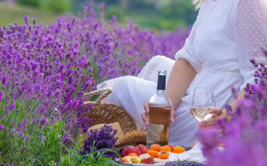 a girl in a lavender field pours wine into a glass. Relaxation.