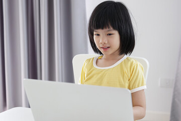 little asian girl student study online using laptop computer at home