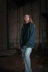 Portrait of a young beautiful fair-haired girl in a low key on a dark background.