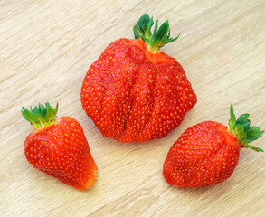 Top view of three large ripe red strawberries on a wooden table.
