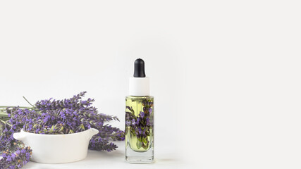Glass bottle of Lavender essential oil with fresh lavender flowers and dried lavender seeds on...