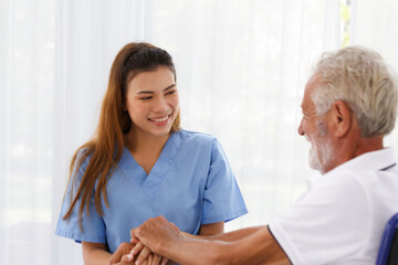 female doctor helping care holding hands to encourage talk Caucasian older man, older adult, patient in a wheelchair