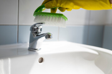 girl in rubber gloves with a brush does cleaning in the bathroom washbasin