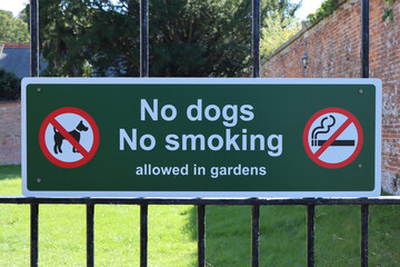A sign on the metal gate into the grounds of the public garden informing that no Dogs or smoking is...