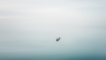 Fototapeta premium small cargo container ship floating in sea motion blur aerial view