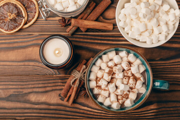 Cup of tasty cocoa drink and marshmallows in blue cup.Spices and marshmallows for winter drinks on brown texture table.Winter hot drink.Hot chocolate with marshmallow and spices.Copy space.