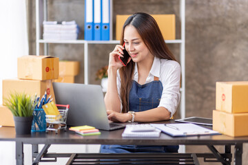 Startup SME small business entrepreneur of freelance Asian woman using a laptop with box Cheerful success happy Asian woman her hand lifts up online marketing packaging and delivery SME idea concept