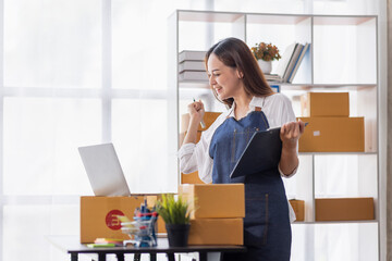 Fototapeta na wymiar Startup SME small business entrepreneur of freelance Asian woman using a laptop with box Cheerful success happy Asian woman her hand lifts up online marketing packaging and delivery SME idea concept