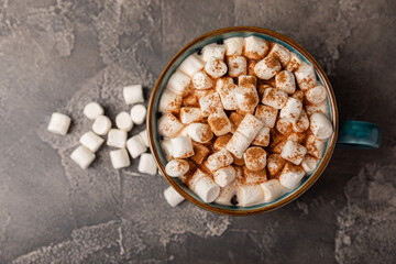 Cup of tasty cocoa drink and marshmallows in blue cup.Spices and marshmallows for winter drinks on black texture table.Winter hot drink.Hot chocolate with marshmallow and spices.Copy space.