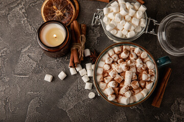 Cup of tasty cocoa drink and marshmallows in blue cup.Spices and marshmallows for winter drinks on black texture table.Winter hot drink.Hot chocolate with marshmallow and spices.Copy space.