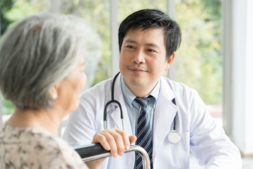 Happy doctor taking care elderly asian woman on wheelchair at the hospital. People and health care concept