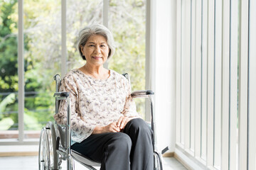Happy elderly adult retired asian woman sit on wheelchair at home. Smiling asian senior old grandma...