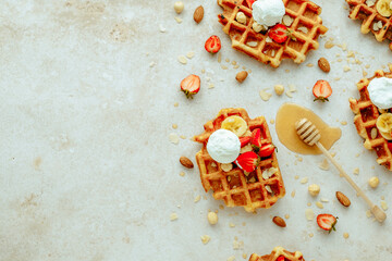 Traditional Belgian waffle with ice cream, strawberry, banana, nuts and honey. Summer sweet breakfast concept. Flat lay, top view. space for text. 