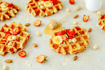 Traditional Belgian waffle with strawberry, banana, nuts and honey. Summer breakfast, cooking concept. Flat lay, top view. space for text. 
