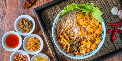 A bowl of Guangxi Liuzhou gourmet snail noodles on a wooden table