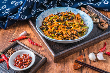 A plate of fish-flavored shredded pork on a wooden table