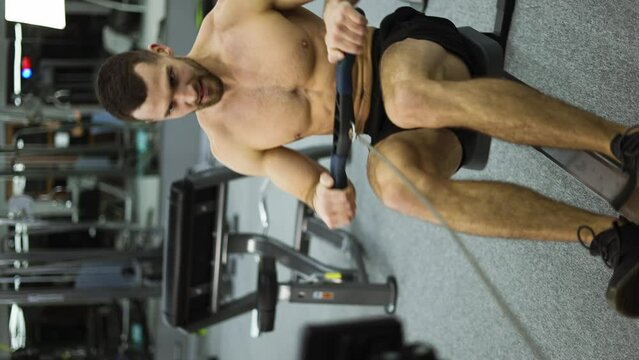 Shirtless athlete training rowing machine exercise intense endurance workout, slow motion