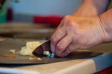 A woman with a knife in the kitchen cuts the ingredients for a dish