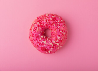 Donut on a pink background.Strawberry donut with pink icing and sprinkles on a paper background.Colorful minimalism concept.Junk food.Sweets.Copy space.Flat lay.Place for text.
