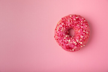 Donut on a pink background.Strawberry donut with pink icing and sprinkles on a paper background.Colorful minimalism concept.Junk food.Sweets.Copy space.Flat lay.Place for text.