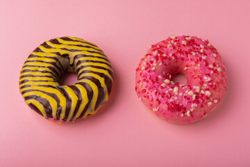 Donuts on a pink background.Chocolate and strawberry donut with yellow and pink icing on a paper background.Colorful minimalism concept.Junk food.Sweets.Copy space.Flat lay.Place for text.