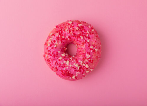 Donut on a pink background.Strawberry donut with pink icing and sprinkles on a paper background.Colorful minimalism concept.Junk food.Sweets.Copy space.Flat lay.Place for text. - Powered by Adobe