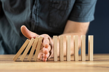 Businessman hand stop falling off wood block, planing and strategy concept, business disruption,...