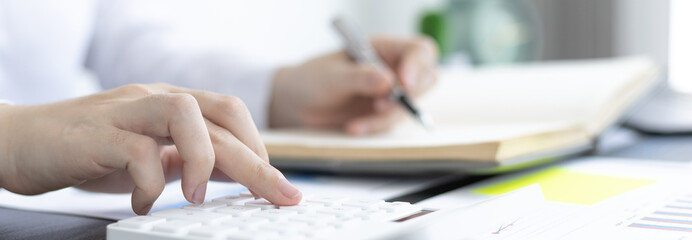 Head of accounting is recording the company's financial growth statistics using graphs as a reference for reviewing and analyzing the results, Taking notes and analyzing data graphs in office.