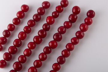Cherry pattern. Fresh red fruits lay in diagonal lines on white background. Copy space for text