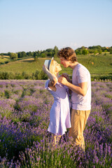 couple in purple lilac white outfit hugging, kissing in lavender field, photo session. man is holding woman in hands. Romance